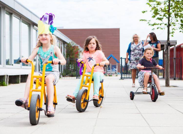 Kinderopvang met fietsende kinderen en pedagogisch medewerkers